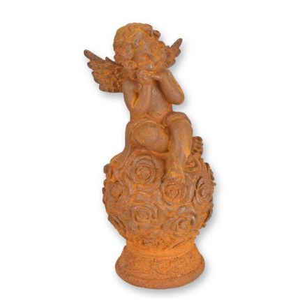 Gusseisenfigur Putte, rostfarben, A RUSTY CAST IRON FIGURINE OF A PUTTO SITTING ON BALL