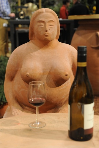 Dicke Frau aus Terracotta bei einem Glas Wein